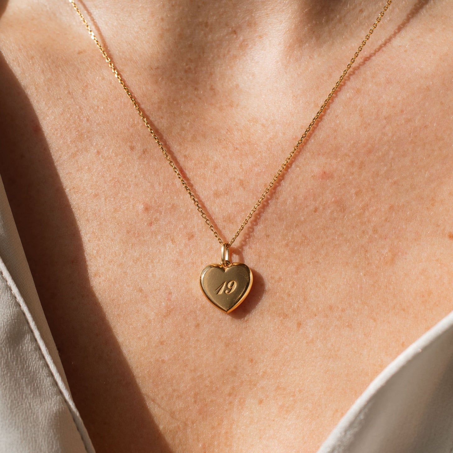 Custom numbers engraved on a gold heart necklace pendant by Grace Personalized with customizable chains