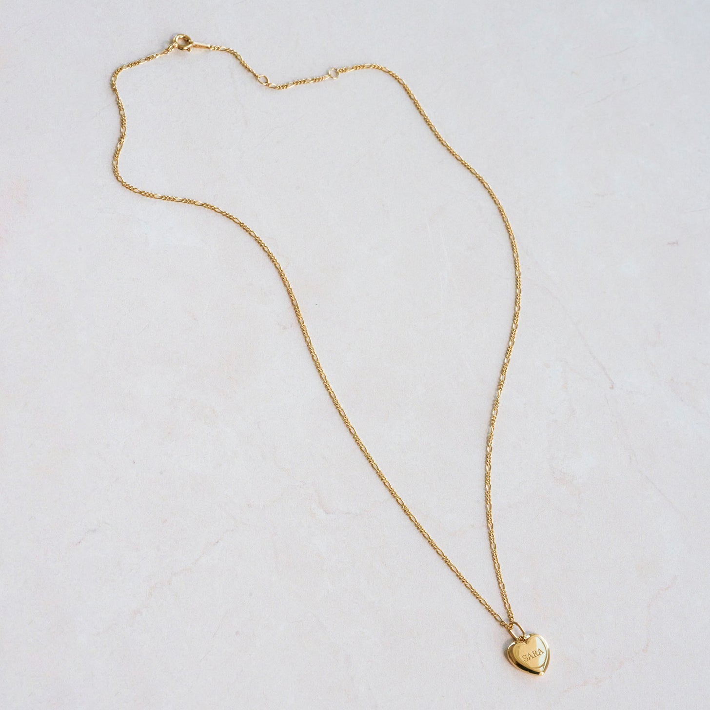 Engraved name on a custom heart pendant with figaro chain necklae